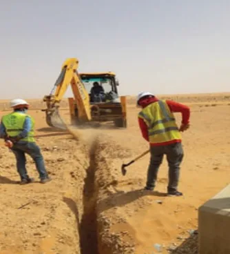 Field crew excavating a cable trench in desert terrain